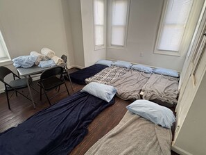 A dormitory room with two beds, a table, and chairs. - Temple Apartment Unit 1 2 bedrooms (Philadelphia)