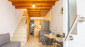 Un intérieur chaleureux avec un escalier menant à la cuisine, un coin repas avec une table et des chaises, et un canapé gris.