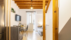 Une cuisine compacte avec un coin repas, un canapé et un téléviseur fixé au mur.