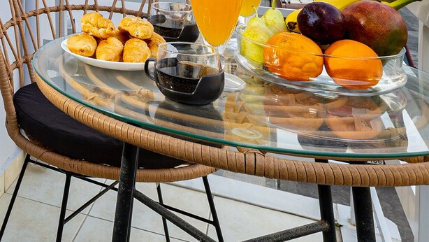 Une table dressée avec de la nourriture et des boissons sur un balcon donnant sur une rue et des immeubles.