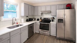 A modern kitchen with grey cabinets, stainless steel appliances, and a window providing natural light. - Music Weekend in Woodstock| Madlife|Lamplighter|Am (Woodstock)