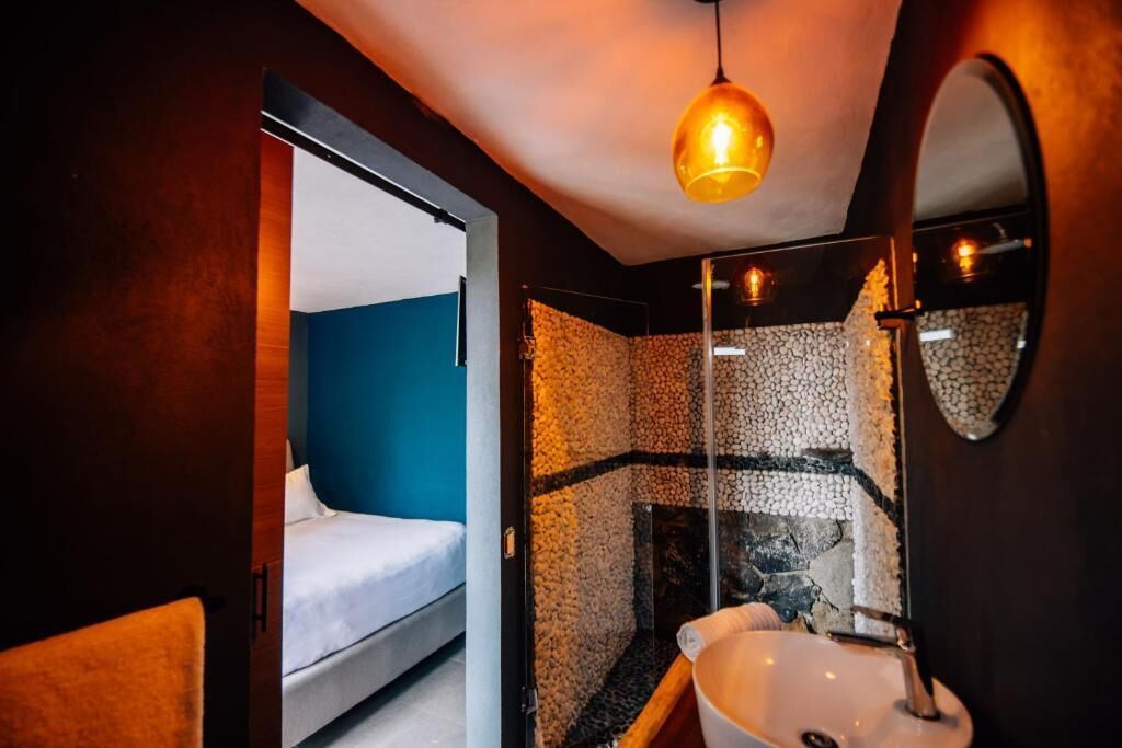 A compact room with a bed, a sink, and a mirror.