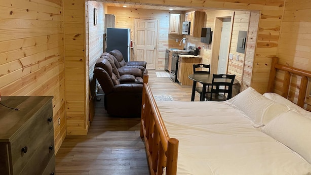 L’intérieur d’un chalet en bois comprend un canapé, un lit, une table à manger et un coin cuisine.