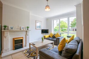 A living room with a fireplace, a sofa, a coffee table, and a TV.