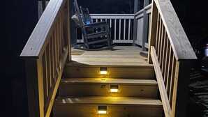 Een houten trap met ingebouwde verlichting die uitkomt op een terras.