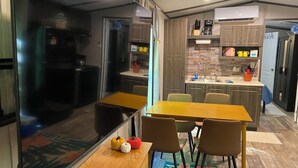 Een kleine keuken met een eethoek, een koelkast, een koffiezetapparaat en een raam.