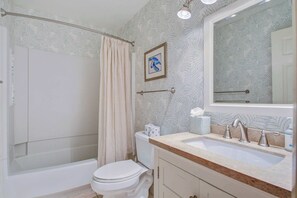 Ein Badezimmer mit Badewanne, Toilette, Waschbecken und Duschvorhang.