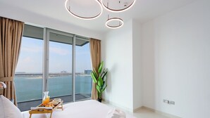 Camera d'albergo moderna con un letto grande, un tavolino con la colazione, una pianta e vista sul mare.