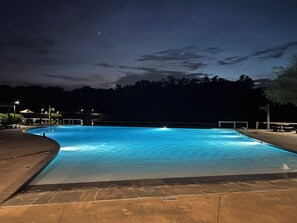 A nighttime swimming pool with a clear water surface, surrounded by a paved deck and a low wall. - Charming 2-bedroom cottage with GOLF CART at The Waters (Pike Road)