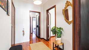 A hallway with wooden flooring, a white door, and a mirror with an ornate frame. - Porto Essence Apartment (Porto)