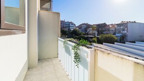 A balcony with a white railing, a small tiled area, and a view of colorful buildings in the background. - Porto Essence Apartment (Porto)