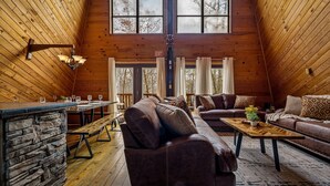 Ein gemütliches, holzgetäfeltes Interieur mit einer Steinbar, Ledersofas und einem Essbereich.
