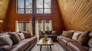 Ein gemütliches Loft-Zimmer mit zwei Ledersofas, einem Holztisch und einem großen Fenster mit Vorhängen.
