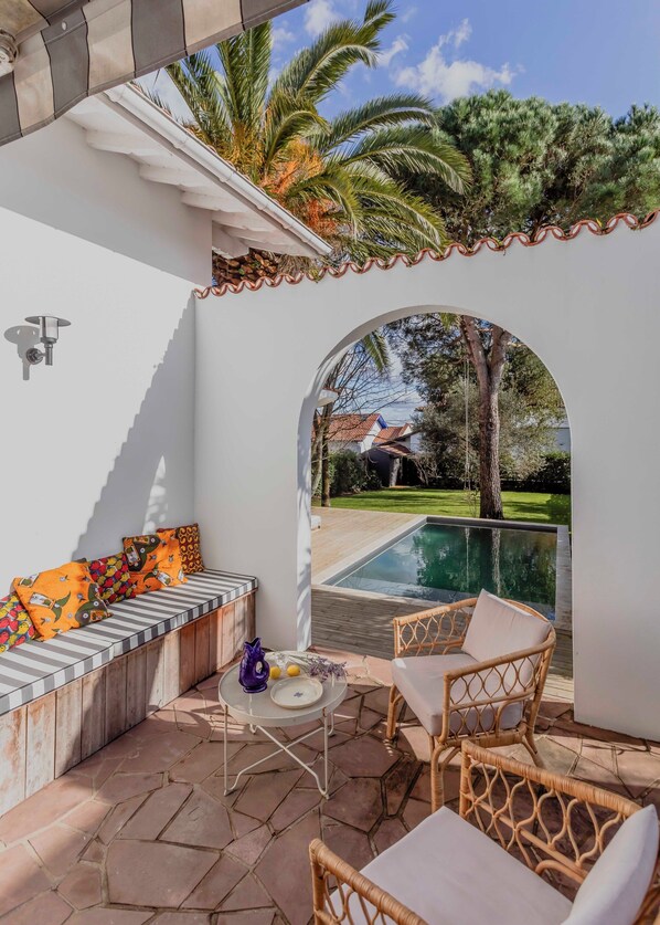 A patio with a pool, seating area, and outdoor furniture.