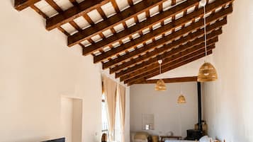 Amplia sala de estar con techo alto, vigas de madera, televisor de pantalla plana, mesa de comedor y sofá.