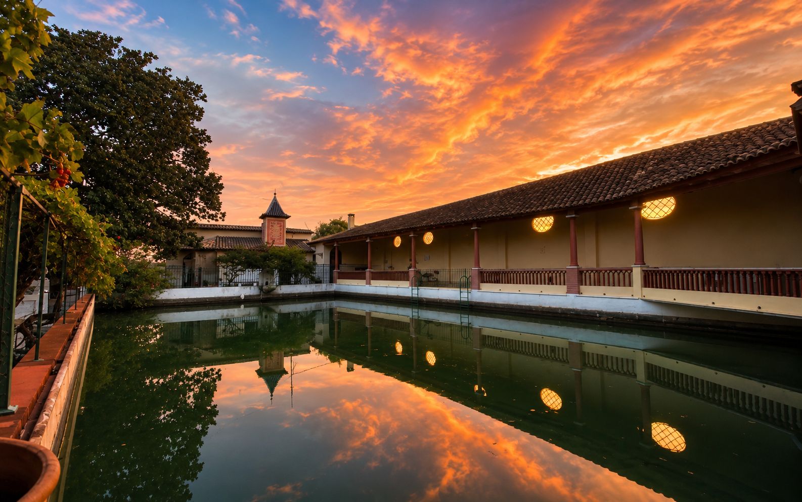 Une cour paisible avec un bassin aux eaux calmes, une architecture traditionnelle et un ciel dégagé.