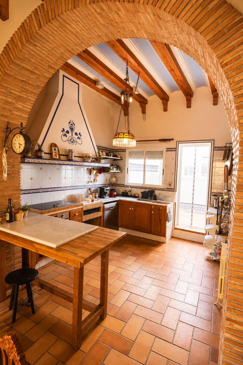 Una cocina con mesa de madera, armarios y lámpara colgante.