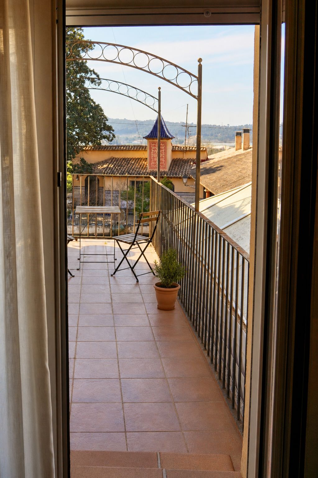 En balkon med udsigt til en bygning med et blåt tag og flisegulv.