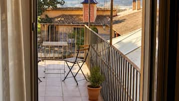 En balkon med udsigt til en bygning med et blåt tag og flisegulv.