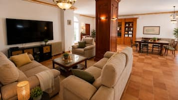Una sala de estar con televisor de pantalla plana, sofá, mesa de centro y comedor con mesa y sillas.