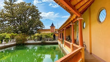 Un patio con piscina, un edificio tradicional con techo de tejas y un árbol.