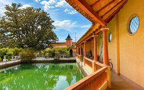 A courtyard with a pool, a traditional building with a tiled roof, and a tree.