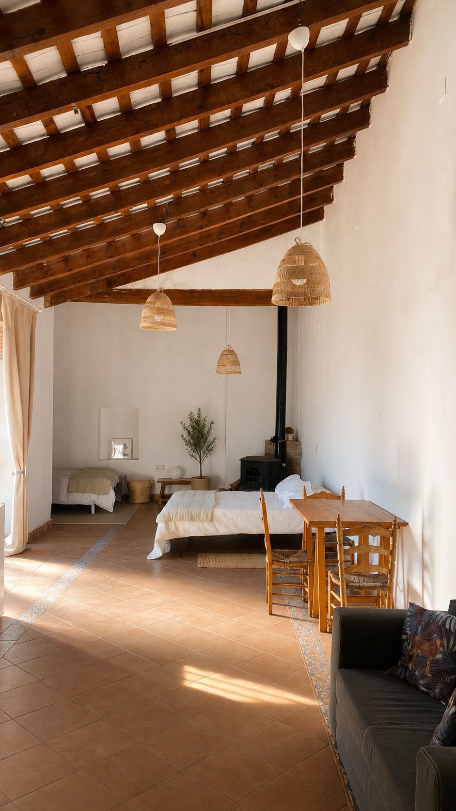Ein Schlafzimmer mit einem Bett, einem Holztisch und einer Couch. Es gibt ein Fenster und eine Wandheizung.