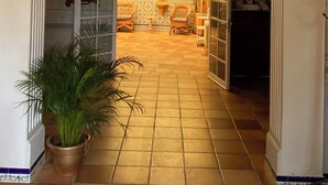 An arched doorway leading to a room with a tiled floor and a potted plant.