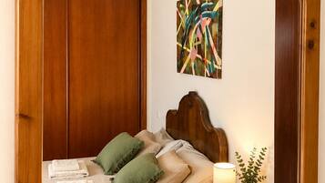 Una cama con cabecera de madera, una mesita de noche con lámpara y un espejo.