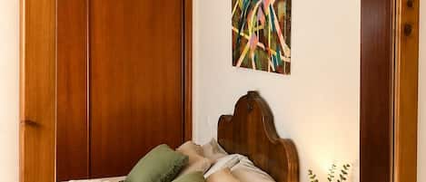 A bed with a wooden headboard, a bedside table with a lamp, and a mirror.