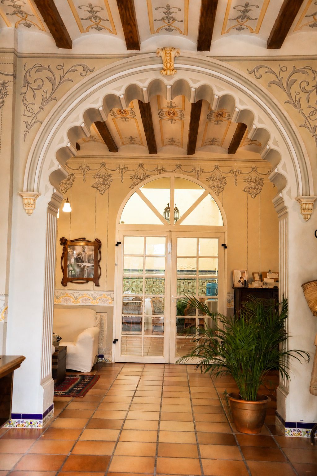 An interior with a tiled floor, a large arched doorway, and a potted plant.
