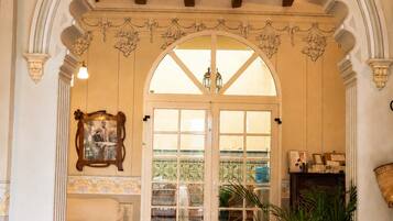 An interior with a tiled floor, a large arched doorway, and a potted plant.