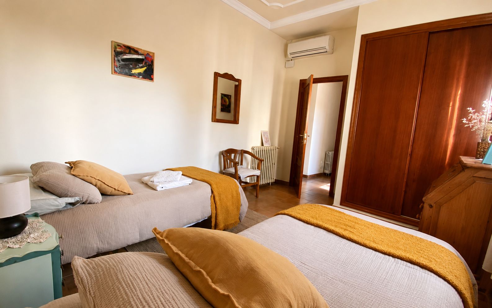 Habitación de hotel con dos camas, una silla, un escritorio y un armario.