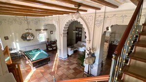 A spacious room with a pool table, a staircase, and a view of a garden.