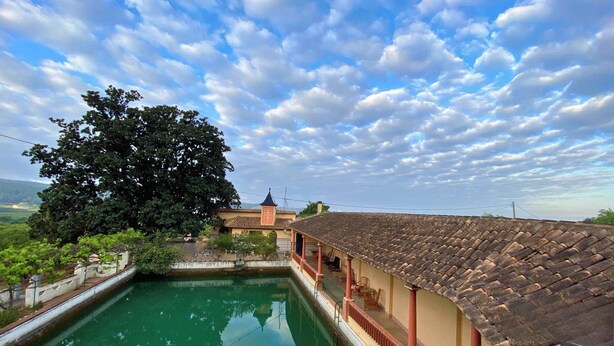 A traditional building with a tiled roof, a courtyard with a pool, and a large tree.