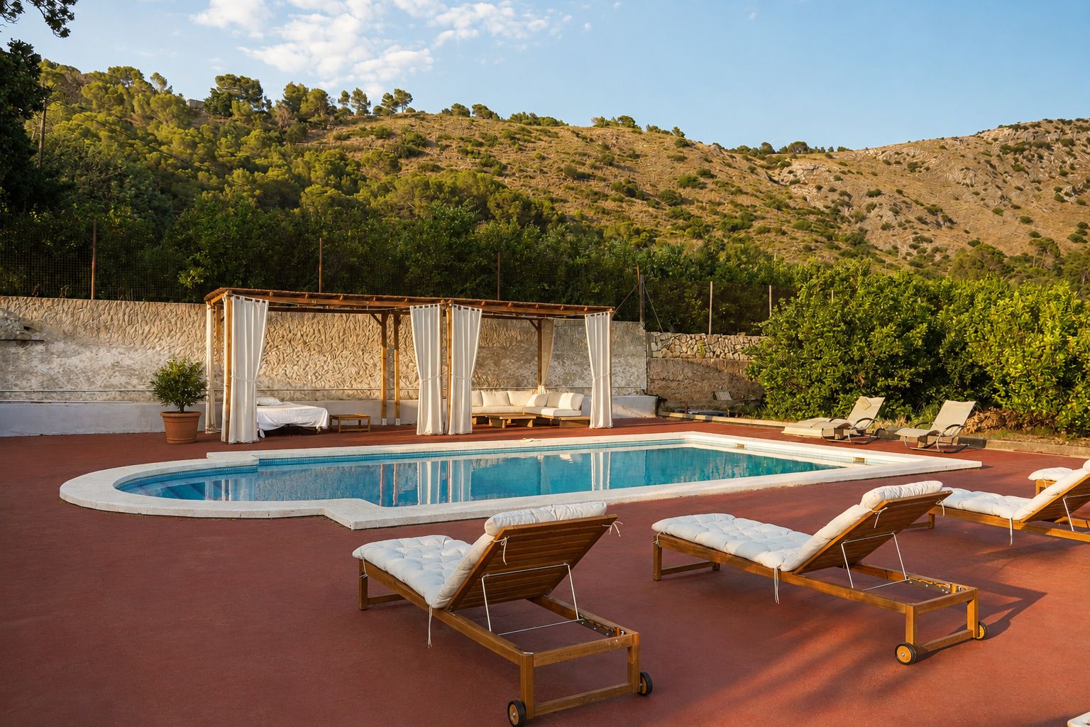Zona de piscina con sillones de descanso, una pérgola y vistas a una colina.