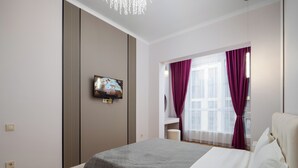 A modern bedroom with a bed, a television mounted on the wall, and a window with curtains.