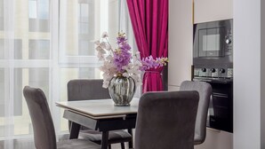 A modern kitchen with a dining table, chairs, and a vase of flowers.