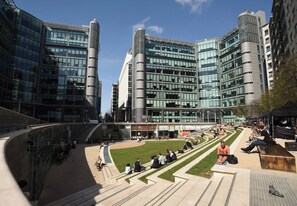 A modern urban plaza with a baseball field, surrounded by high-rise buildings with reflective glass facades. - Whole Flat in Little Venice (London)