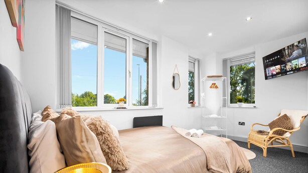 A modern bedroom with a large bed, a television, and a window with a view of greenery. - Uebert Heights| 2Bed| Slp6| Closest to Cannock Town (5min walk)| Free Parking (Cannock)