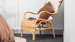 A wicker chair with a fur throw and a pillow, positioned against a white wall with a window above. - Uebert Heights| 2Bed| Slp6| Closest to Cannock Town (5min walk)| Free Parking (Cannock)