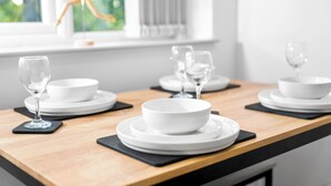 A dining table set with white plates, bowls, and wine glasses, with a window in the background. - Uebert Heights| 2Bed| Slp6| Closest to Cannock Town (5min walk)| Free Parking (Cannock)