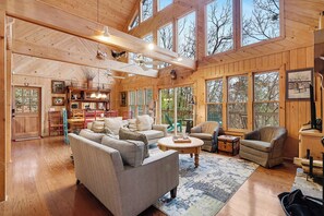 Un interior espacioso de madera con ventanas amplias, un comedor y una zona de estar acogedora.