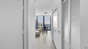 A narrow hallway with a view to a balcony with outdoor seating.