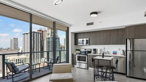 A modern apartment with a balcony, a kitchen, and a city view.