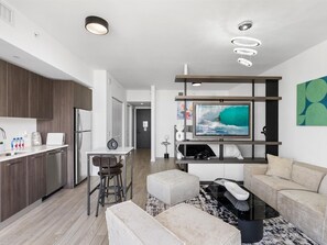 A modern apartment with a kitchen, dining area, and living room. It includes a flat-screen TV, a sofa, a coffee table, and a TV stand. - Luxury Studio Suite City Views Downtown Miami (Miami)