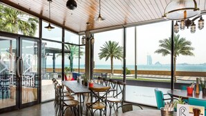 A restaurant with a wooden ceiling, large windows, and a view of the sea. - Luxury 1- Bedroom at Anantara Palm Jumeirah (Dubai)