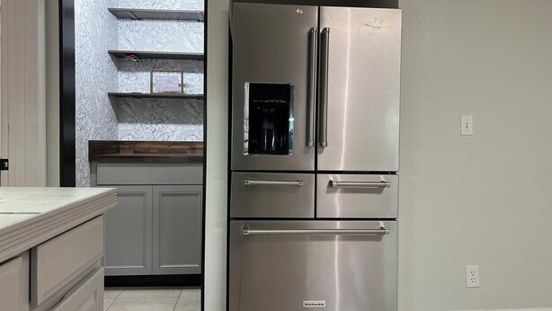 A kitchen with a stainless steel refrigerator, grey cabinets, and a backsplash with floral patterns. - Multi Family House 4Bed/3Bath-Large Fenced Yard with Activities for Whole Family (Fruitland Park)