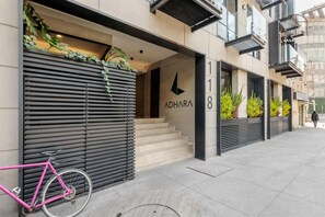 Un edificio moderno con una persiana baja, una escalera que conduce a la entrada y una bicicleta rosa estacionada afuera.