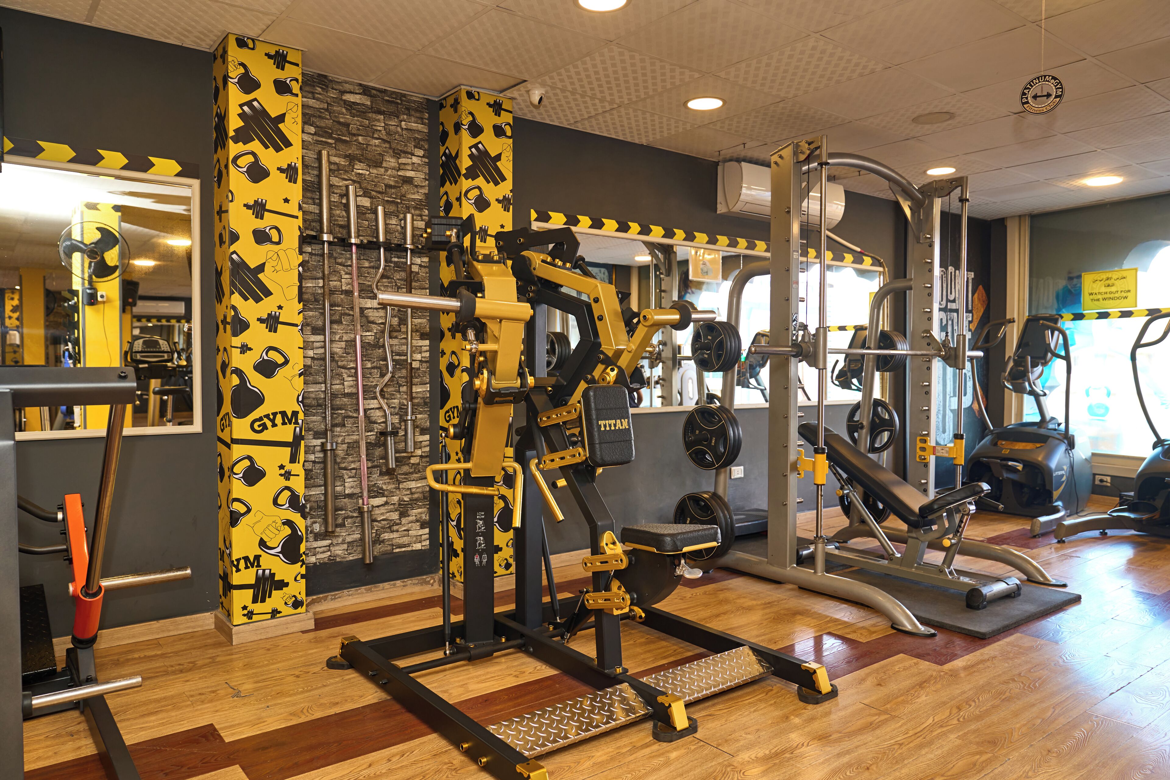 A gym with various exercise equipment, a mirror, and a stone wall.